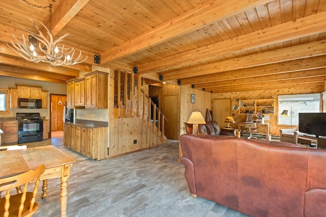 living room featuring a wealth of natural light, beamed ceiling, wood walls, and an inviting chandelier