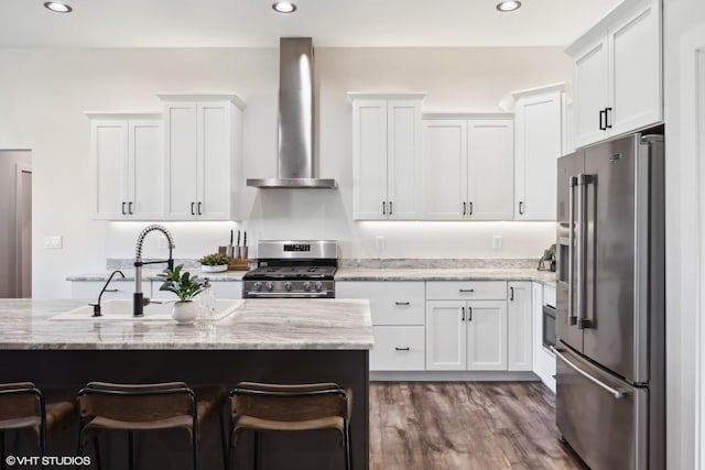 kitchen featuring white cabinetry, dark hardwood / wood-style flooring, wall chimney range hood, and appliances with stainless steel finishes