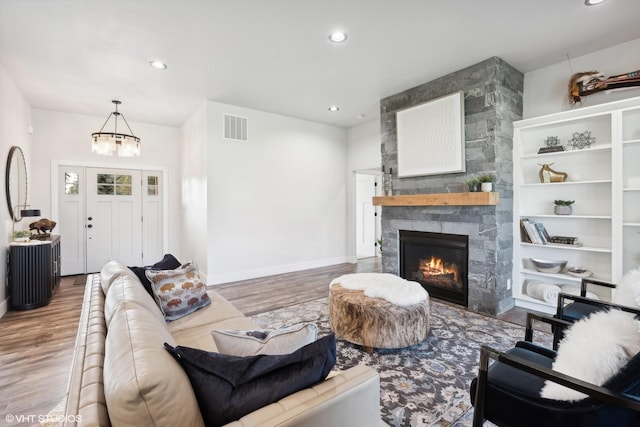 living room with a stone fireplace, an inviting chandelier, and hardwood / wood-style flooring