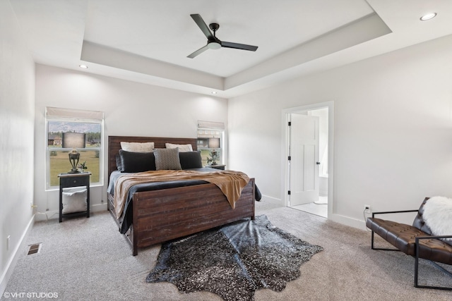 carpeted bedroom with ceiling fan, ensuite bathroom, and a tray ceiling