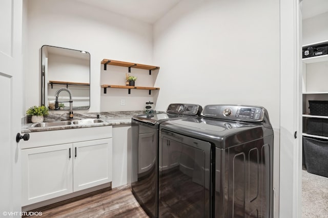 laundry room with washing machine and dryer, sink, cabinets, and hardwood / wood-style flooring