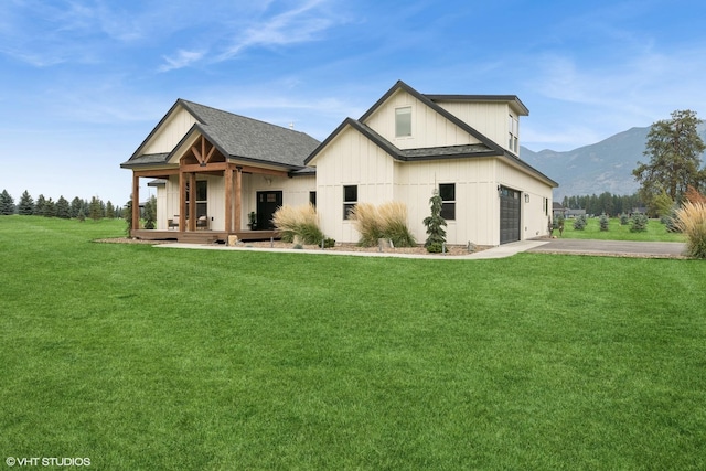 rear view of house featuring a mountain view, a garage, and a lawn