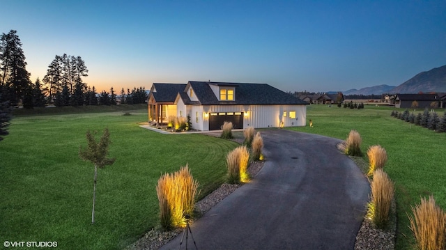 modern inspired farmhouse featuring a mountain view, a garage, and a lawn