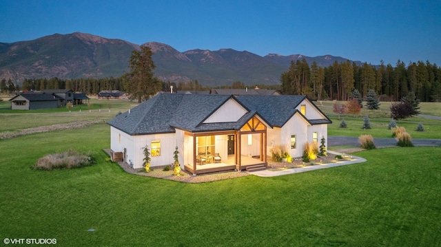 rear view of house with a lawn and a mountain view