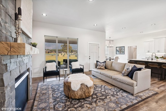 living room featuring a notable chandelier, a fireplace, and dark wood-type flooring