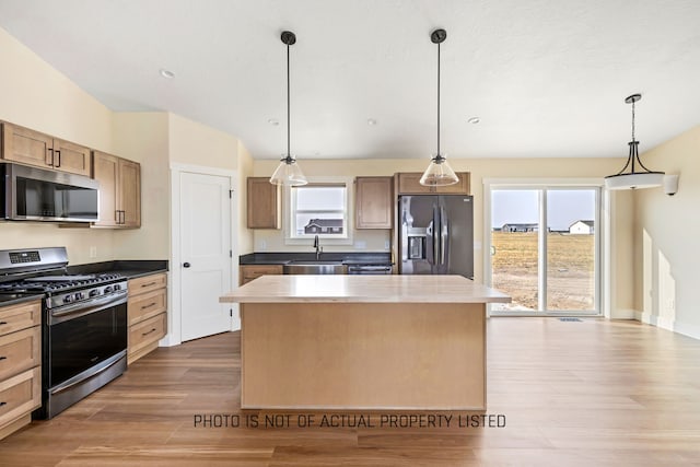 kitchen with plenty of natural light, wood-type flooring, decorative light fixtures, and appliances with stainless steel finishes