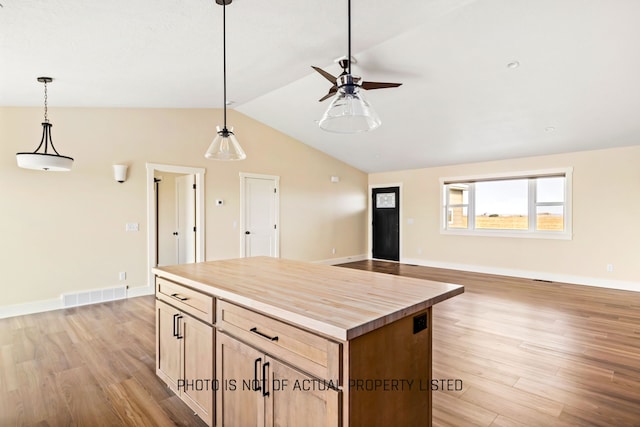 kitchen with butcher block counters, a kitchen island, light hardwood / wood-style floors, and vaulted ceiling