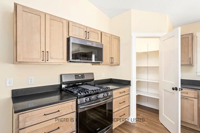 kitchen with light brown cabinets, stainless steel appliances, and light hardwood / wood-style floors