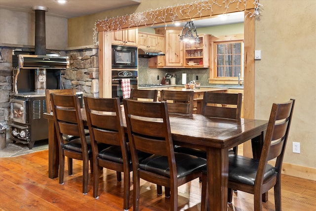 dining space with a wood stove, light wood-style floors, and baseboards