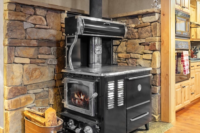 interior details featuring wood finished floors, a wood stove, and built in microwave