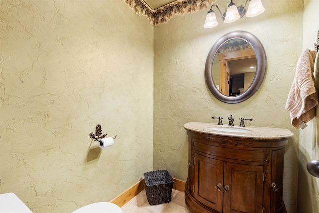 bathroom featuring toilet, a textured wall, tile patterned floors, and vanity