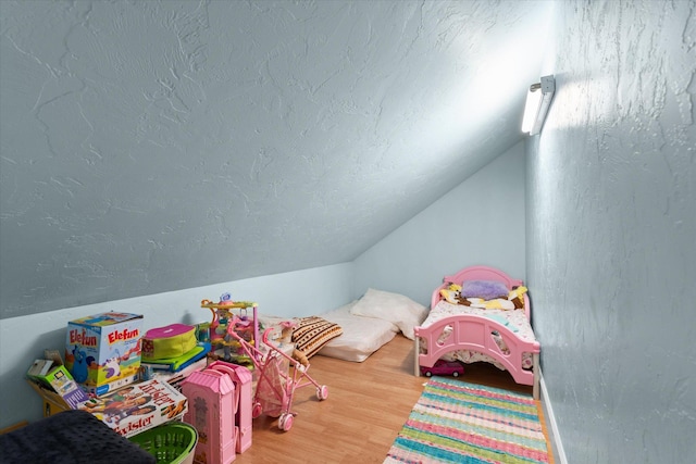 recreation room with lofted ceiling, a textured ceiling, and wood finished floors