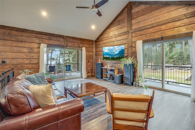 living room with hardwood / wood-style flooring, wooden walls, high vaulted ceiling, and a wealth of natural light