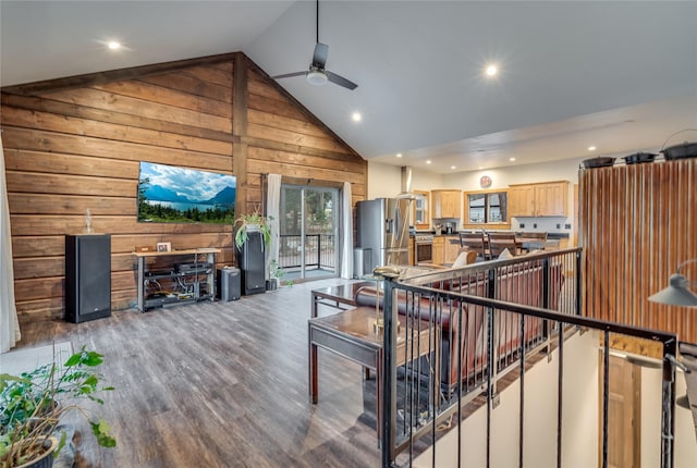 living room with ceiling fan, wood walls, wood-type flooring, and high vaulted ceiling