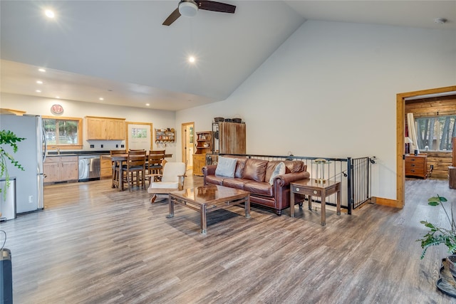 living room featuring ceiling fan, sink, high vaulted ceiling, and wood-type flooring