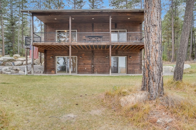 rear view of house featuring a balcony and a yard