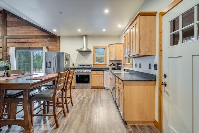 kitchen featuring sink, wall chimney exhaust hood, stainless steel appliances, light hardwood / wood-style flooring, and light brown cabinetry