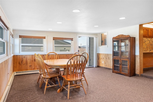 carpeted dining space with a baseboard radiator, wainscoting, wooden walls, and recessed lighting