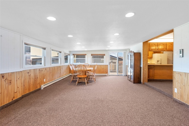 carpeted dining room with a baseboard heating unit, recessed lighting, and wood walls