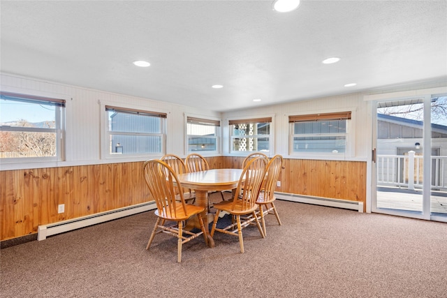 dining room featuring carpet floors, wood walls, and a baseboard radiator