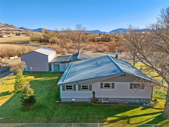 rear view of house with fence, a mountain view, and a lawn