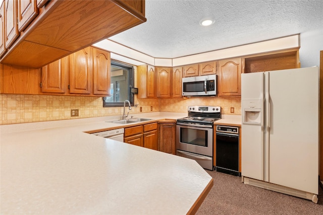 kitchen featuring stainless steel appliances, light countertops, decorative backsplash, a sink, and a textured ceiling