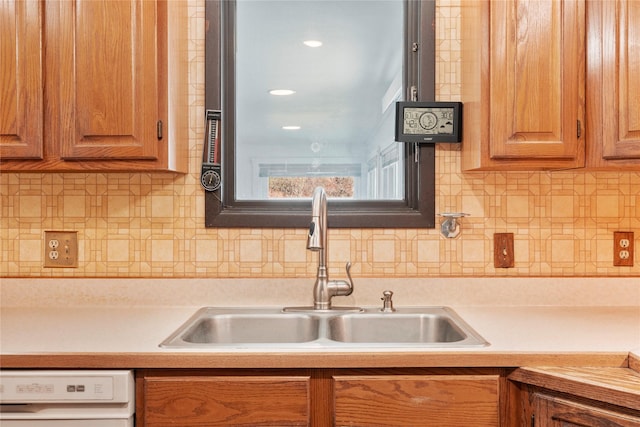 kitchen featuring brown cabinets, dishwasher, light countertops, and a sink