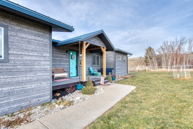 view of exterior entry with a wooden deck and a yard