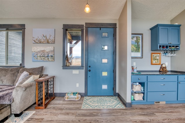 foyer entrance with a wealth of natural light, a textured ceiling, and light hardwood / wood-style floors