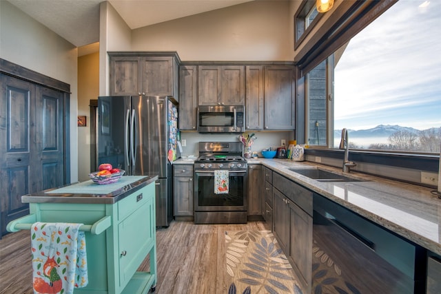 kitchen featuring sink, light hardwood / wood-style flooring, a mountain view, stainless steel appliances, and light stone countertops