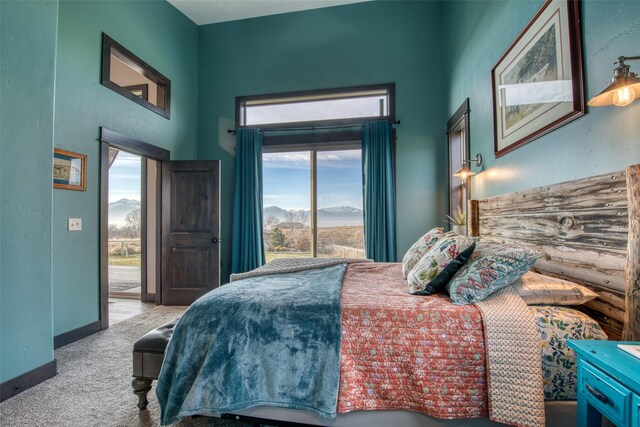 bedroom featuring light colored carpet, a mountain view, and access to outside