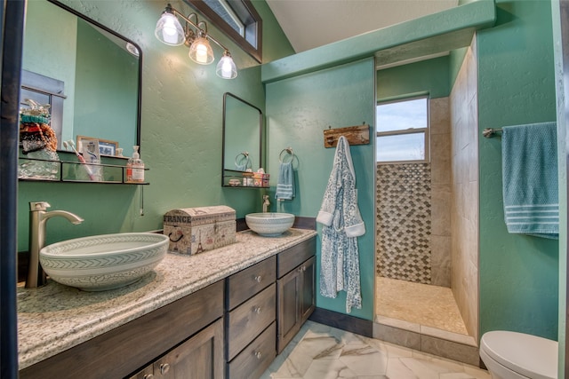 bathroom with tiled shower and vanity