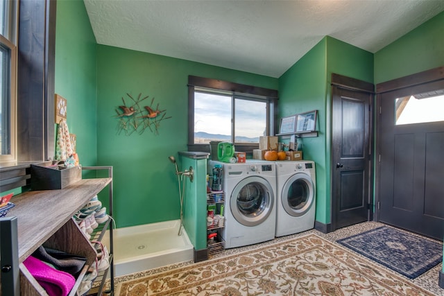 washroom with a healthy amount of sunlight, washing machine and dryer, and a textured ceiling