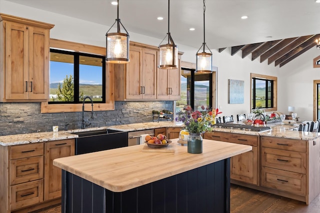 kitchen featuring vaulted ceiling with beams, stainless steel appliances, a sink, a kitchen island, and decorative light fixtures