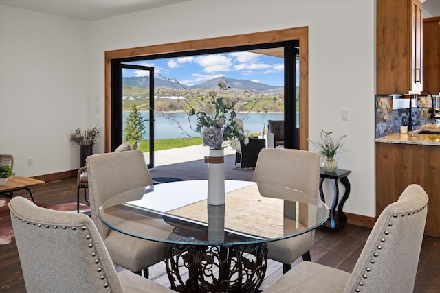 dining area featuring a wealth of natural light, dark wood-style flooring, and a water and mountain view