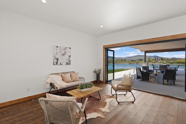 living room with recessed lighting, wood finished floors, a water and mountain view, and baseboards