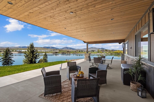 view of patio / terrace featuring outdoor dining space and a water and mountain view