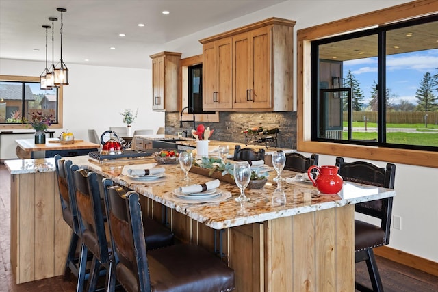 kitchen featuring decorative backsplash, a sink, a wealth of natural light, and pendant lighting