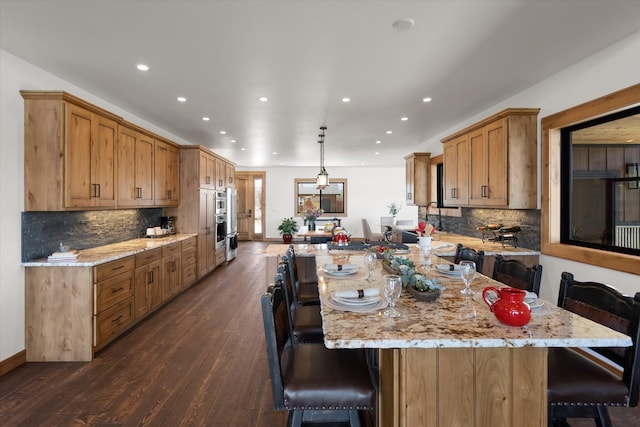 kitchen featuring a large island, decorative light fixtures, a peninsula, and a breakfast bar area