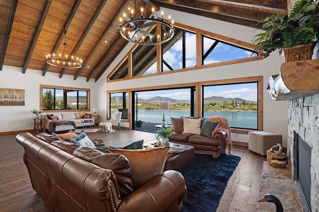 living room featuring high vaulted ceiling, a water view, wood ceiling, a stone fireplace, and a chandelier