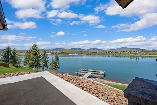 view of dock with a water and mountain view and a patio