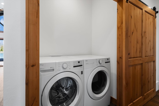 clothes washing area featuring laundry area, a barn door, and washing machine and clothes dryer