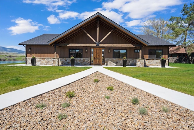 view of front of home featuring stone siding, a front lawn, and a water view