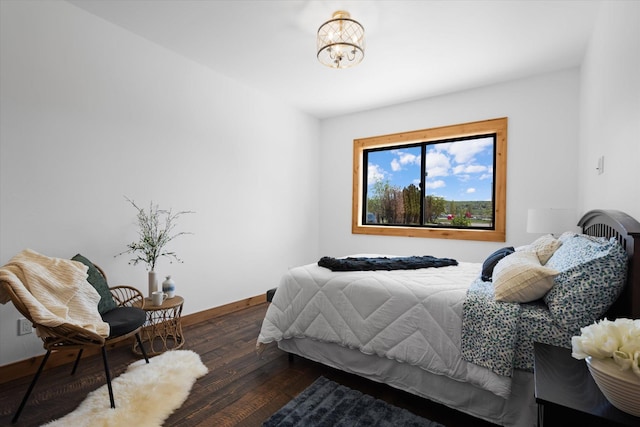 bedroom featuring a notable chandelier, dark wood finished floors, and baseboards