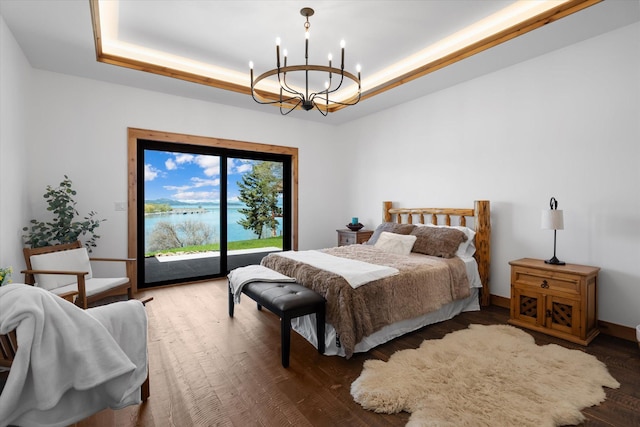 bedroom with a notable chandelier, a tray ceiling, wood finished floors, and access to exterior