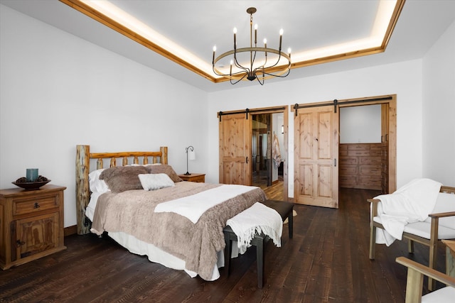 bedroom featuring dark wood-type flooring, a tray ceiling, a barn door, and an inviting chandelier