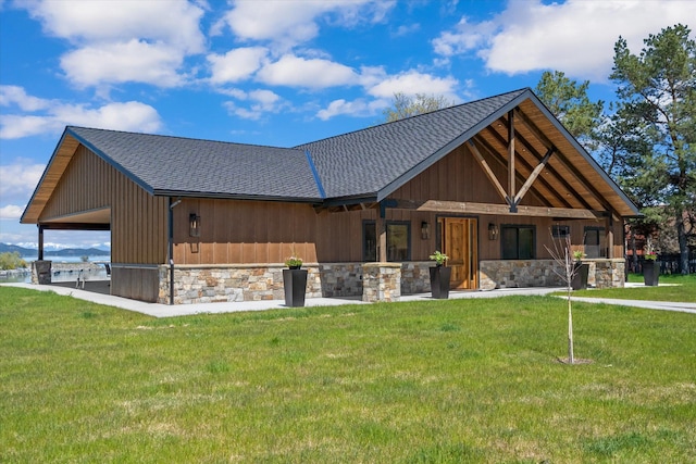 view of front facade featuring stone siding, a front lawn, and roof with shingles