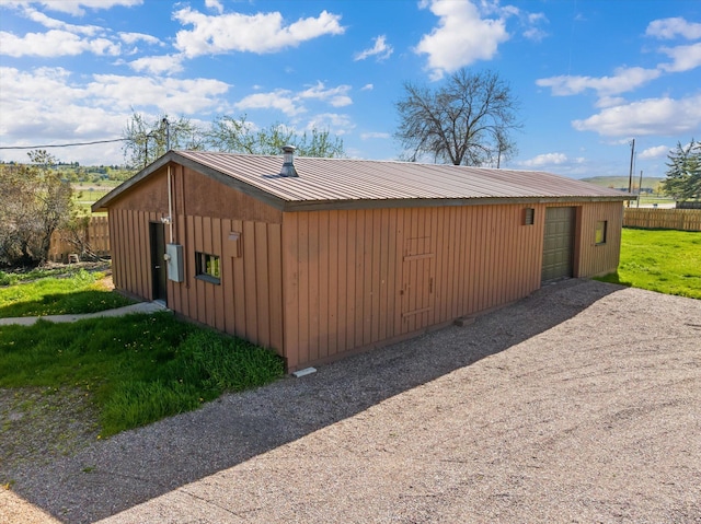 view of side of home featuring gravel driveway, a garage, metal roof, and an outdoor structure