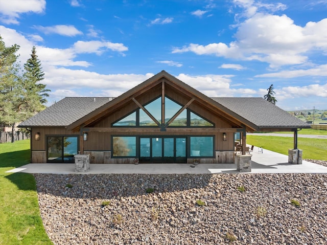 back of house featuring a patio, a shingled roof, and a lawn