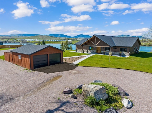 view of front of home featuring a garage, a front lawn, and a water and mountain view